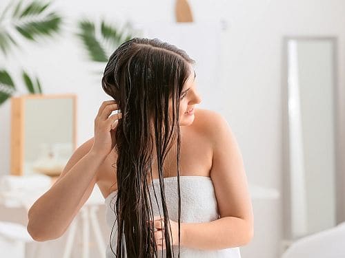 Woman applies conditioner to the hair