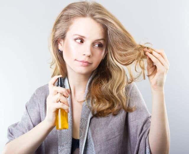 A blonde woman fixes split ends with hair serum