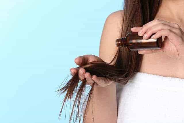 A woman applying keratin oil to hair ends