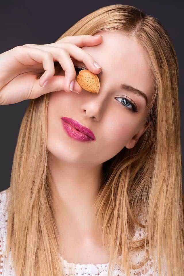 Beautiful blonde girl holding almond nut