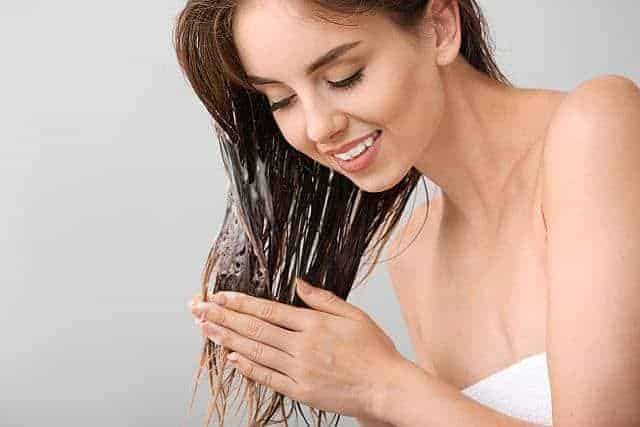 Beautiful young woman washing hair with apple cider vinegar shampoo