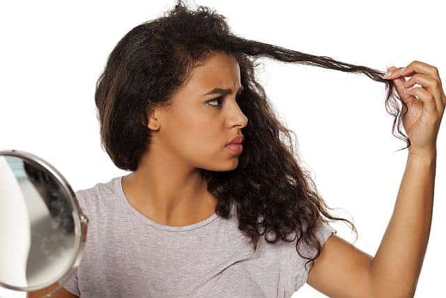 Black-skinned woman inspecting her protein-depleted hair 