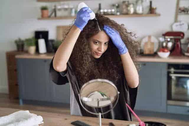 a beautiful young woman applying treatment to her low porosity hair
