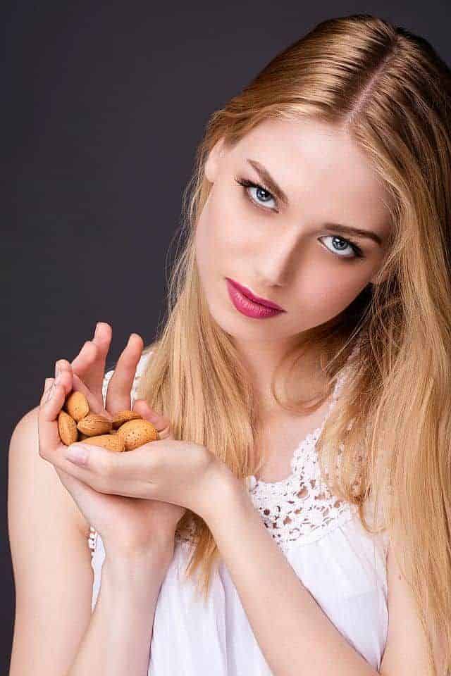 a cute girl holding almond nuts in her hands