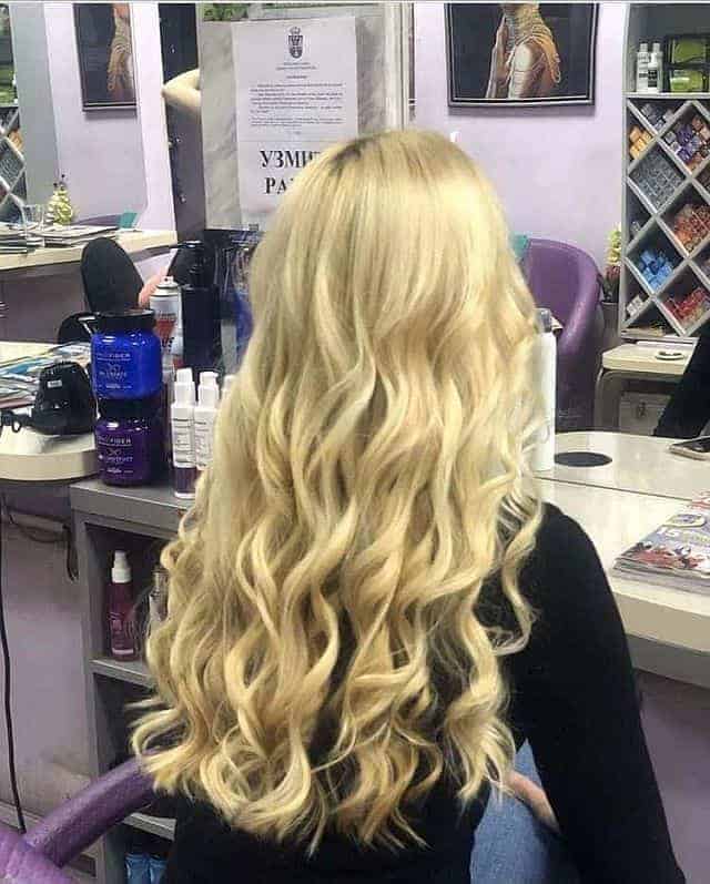 a girl with wavy blonde hair sitting in the salon