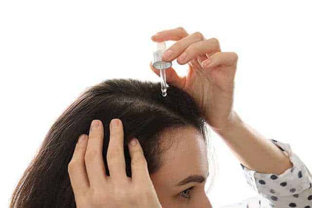 a woman applying jojoba oil to the scalp