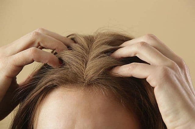 a woman using a powder to cover gray roots