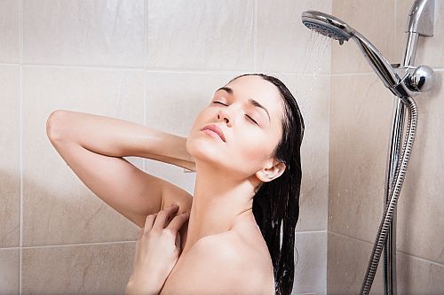 a brunette woman washing hair with the extensions in the shower