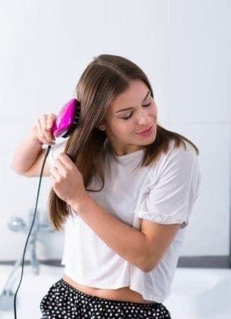 a young woman using a hot straightening brush