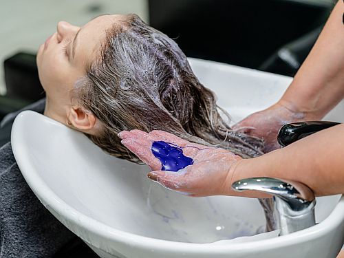 blue shampoo in client's hair in the salon