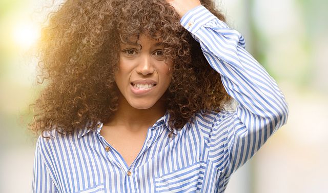 dark-skinned girl is unhappy with her dry curly hair