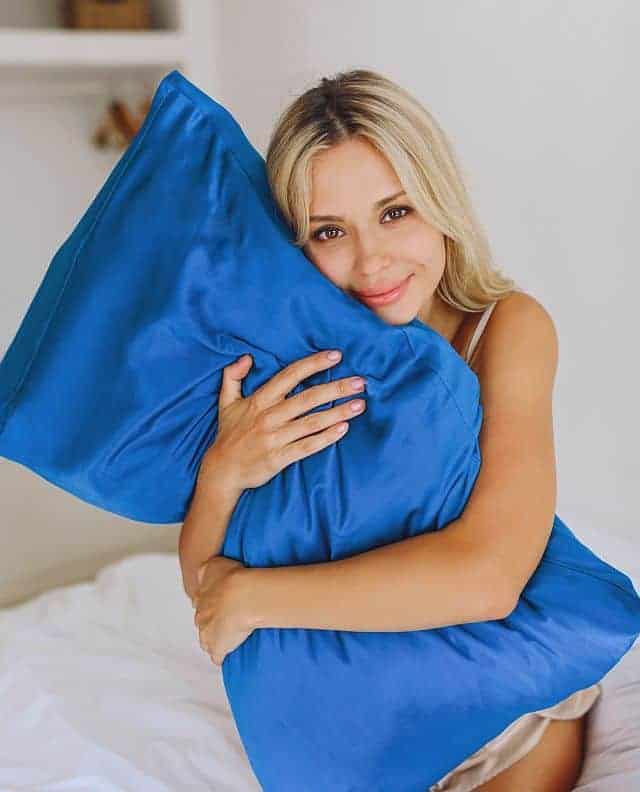 a blonde girl holding a pillow with a silk-cover