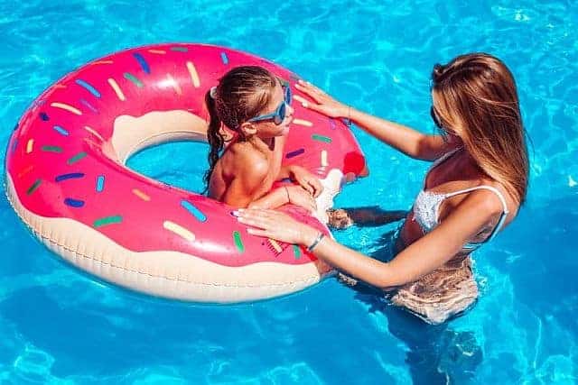 little girl and her mom in playing in a swimming pool