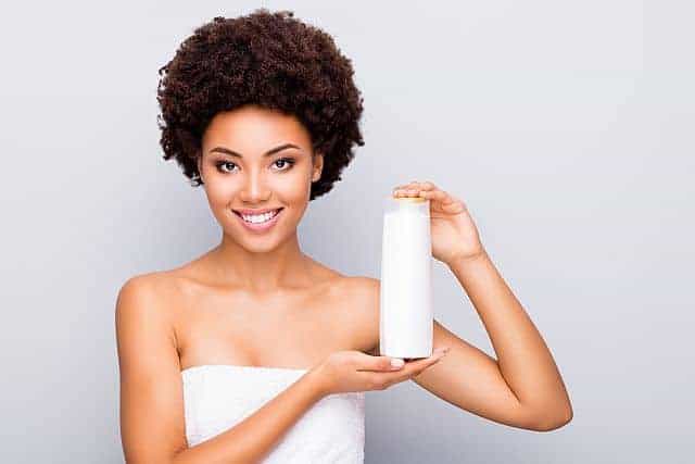woman holding a bottle of a leave-in conditioner for coiled hair