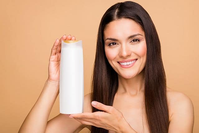 Woman holding the bottle of salt-free shampoo