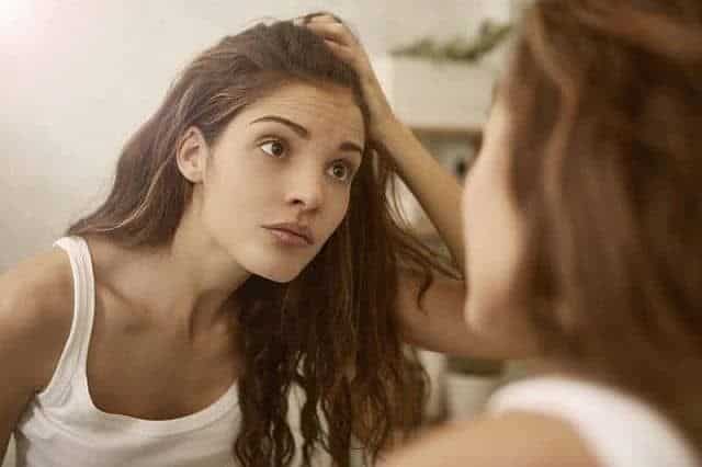 Young girl with dandruff problem in front of the mirror