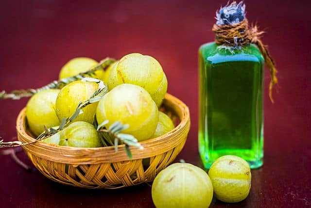 a bottle of amla oil and amla plant fruits