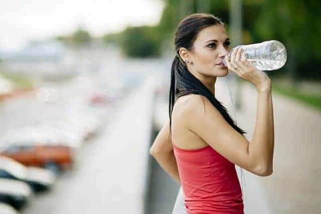 a woman with dry hair drinking water from a bottle