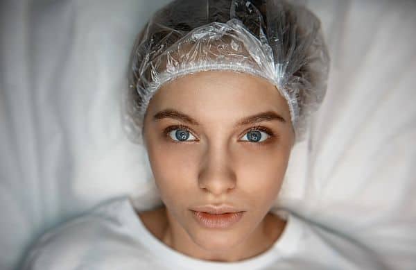 a woman in bed with a shower cap and hair mask in her hair
