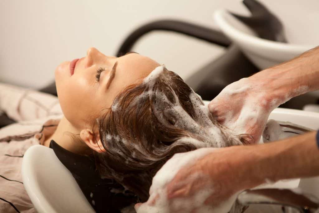 a stylist washes client's hair in the salon