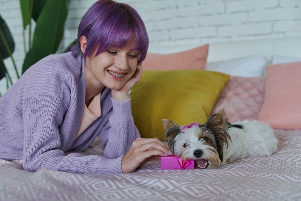 a young woman with purple hair playing with her dog