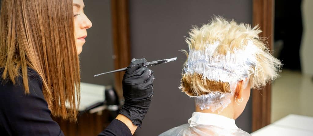 hairdresser using bleach to lighten hair regrowth