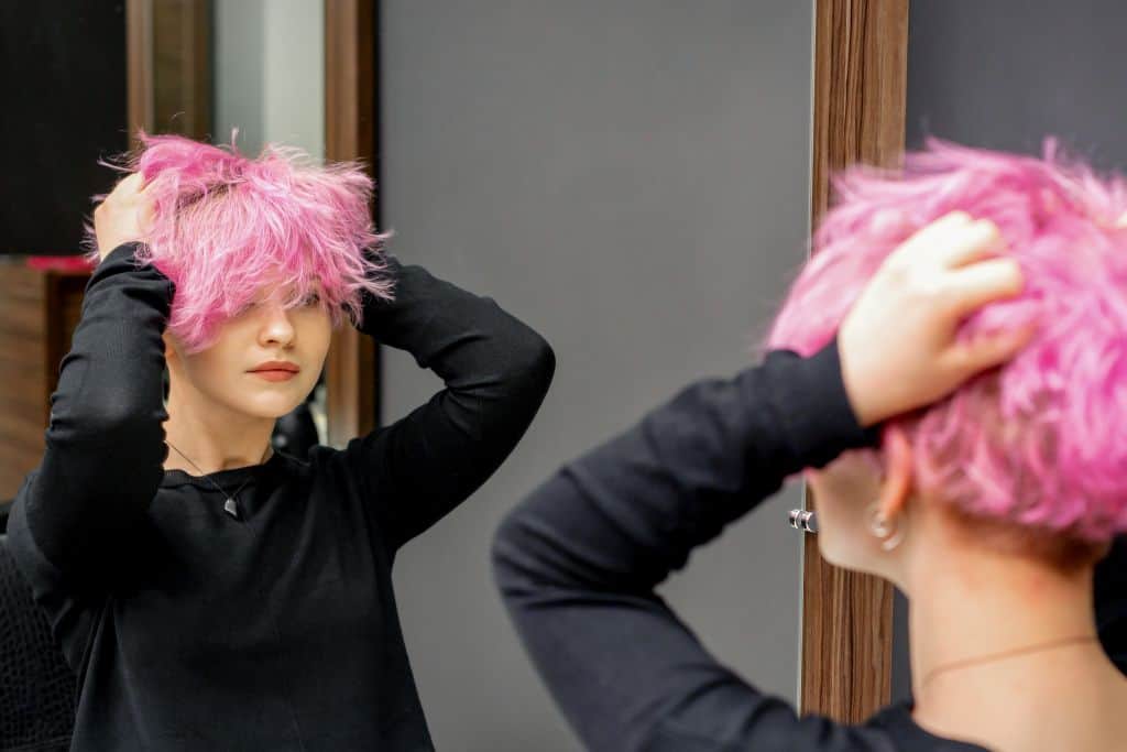 woman in the saloon checking her short pink hair