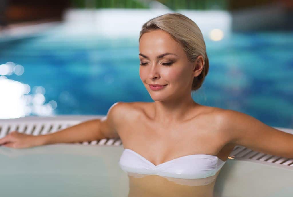 beautiful young woman wearing bikini swimsuit sitting  near the pool