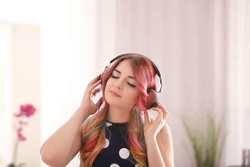 Young woman with colorful dyed hair listening to music