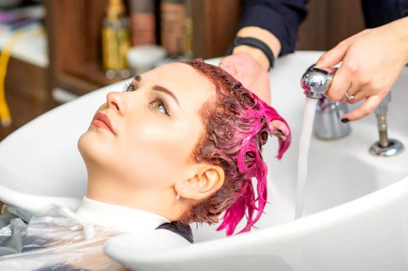hair stylist washing dyed pink hair 