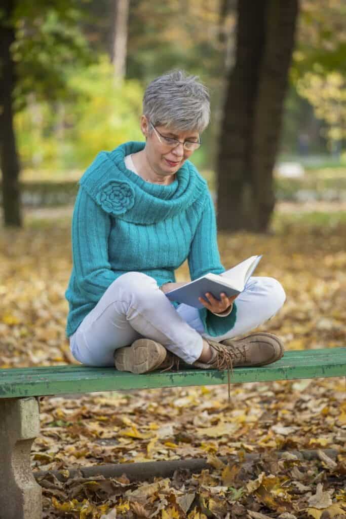 Gray-haired woman in the park reading a book