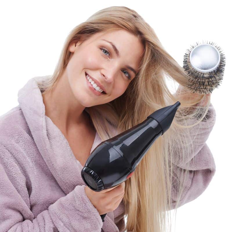 a woman in a robe blow drying her hair