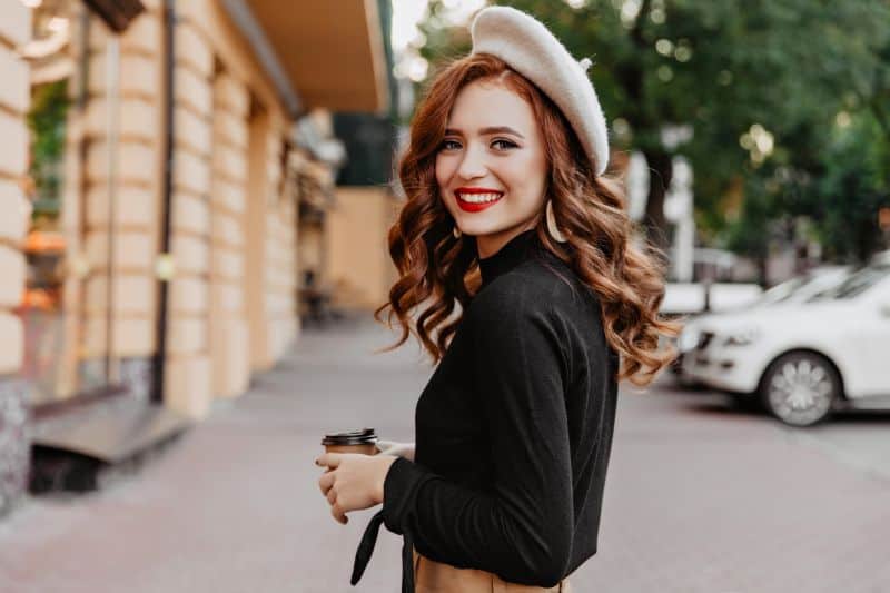 girl with  ginger colored hair in beret looking over shoulder