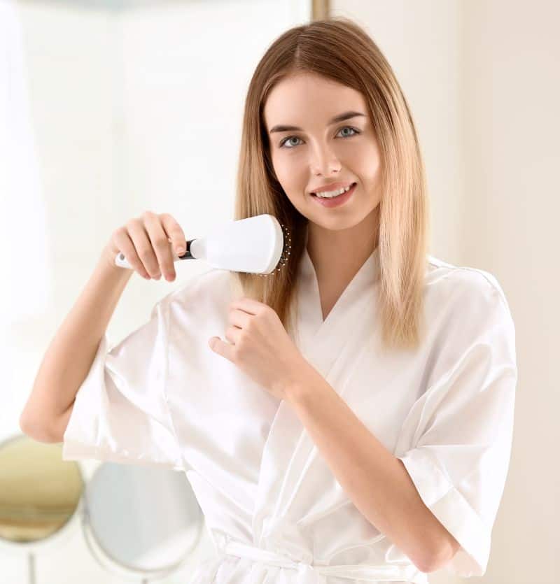 Beautiful woman brushing her healthy hair in morning