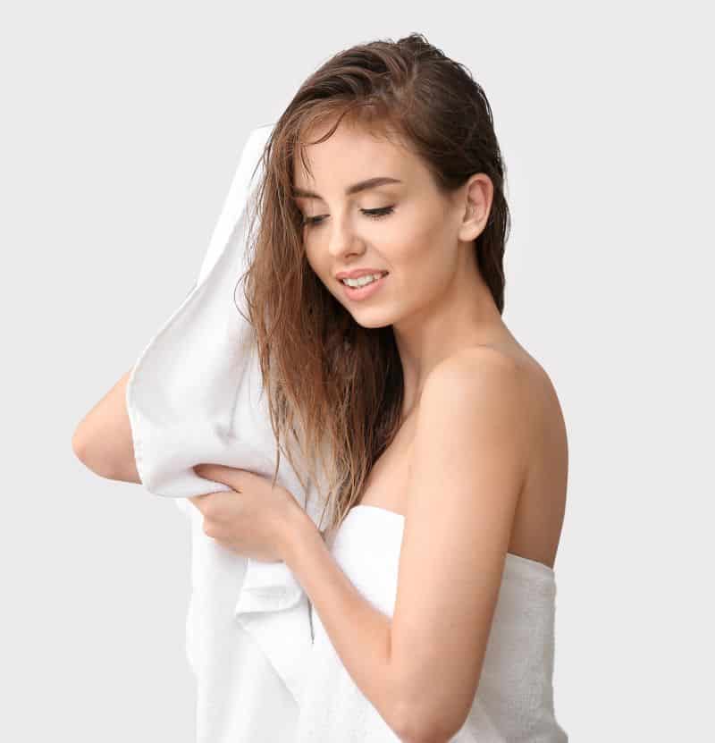 Beautiful young woman wiping her hair after washing