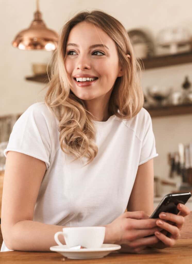 relaxed blond woman with texturized hair using smartphone