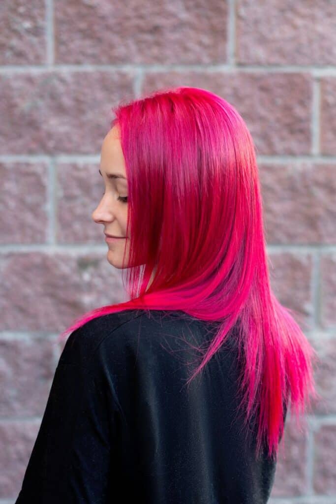 beautiful woman with pink hair on brick wall background