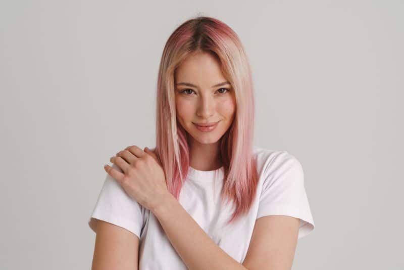 girl with pink hair smiling and looking at camera